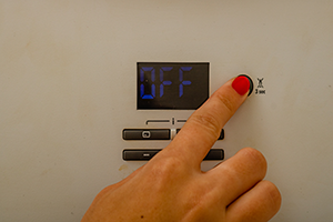 A woman's finger pressing the button to turn off a heater.
