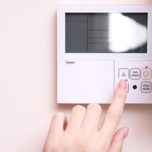 A woman's hand setting a smart thermostat.